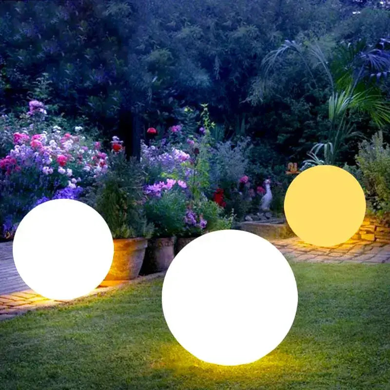 Futuristic outdoor lighting with glowing spheres in a garden surrounded by colorful flowers, enhancing evening ambiance.