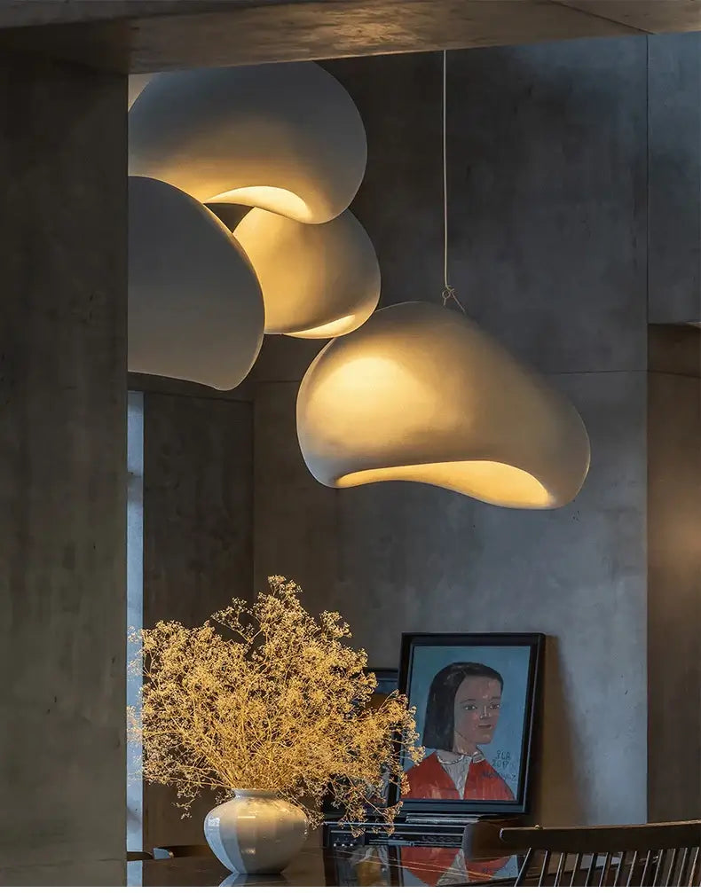 Nordic minimalist pendant lights illuminating a modern dining space with decorative flowers and artwork.