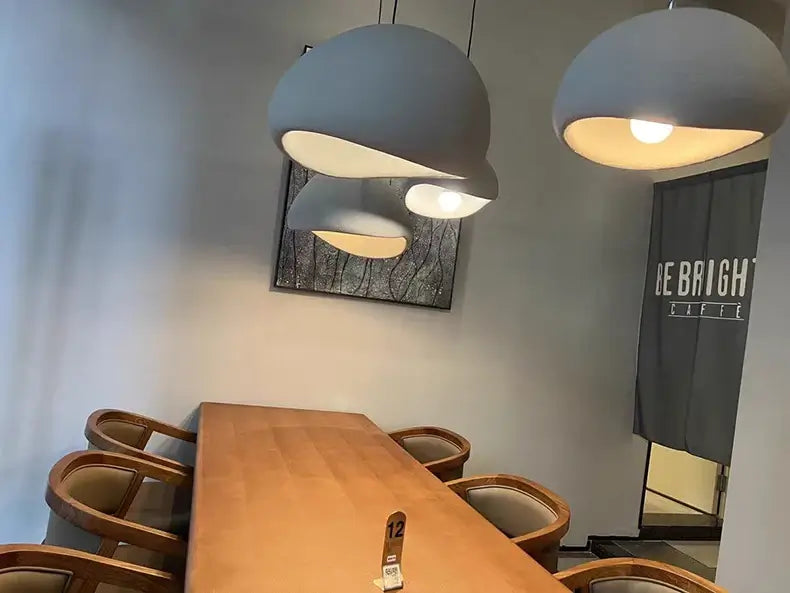 Modern dining room featuring stylish pendant lights and a wooden table with comfortable chairs.