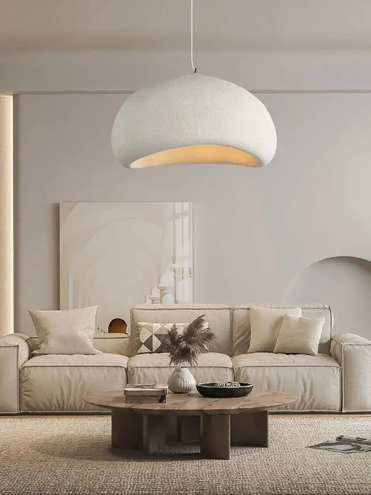 Scandinavian-style pendant light illuminating a modern living room with neutral decor and cozy furnishings.