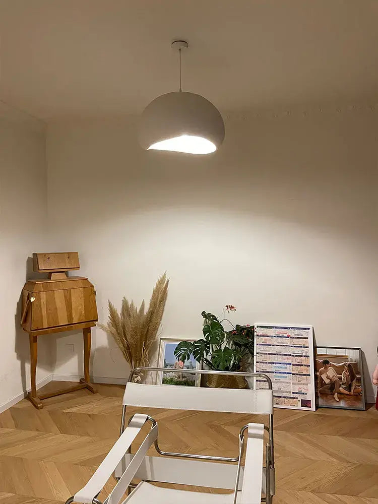 Nordic minimalist pendant light hanging in a cozy room with wooden furniture and plants.