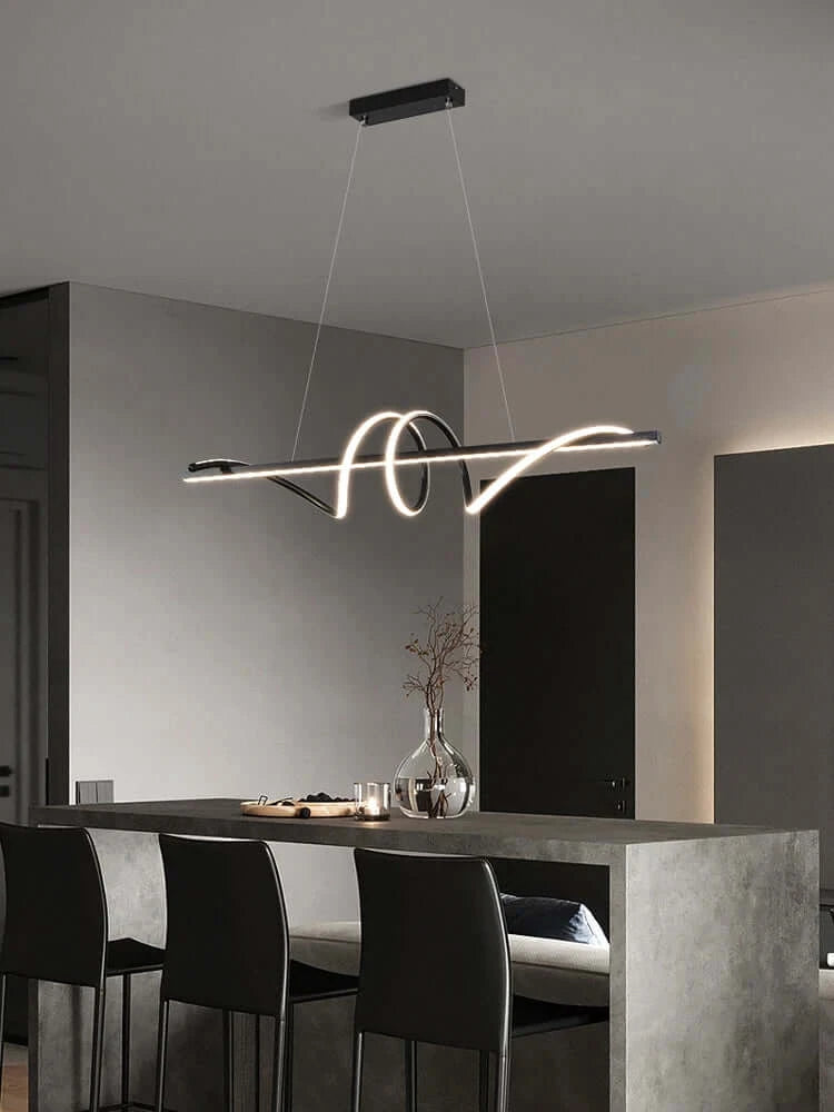 Modern minimalist LED pendant light hanging over a kitchen island with black chairs and sleek decor.