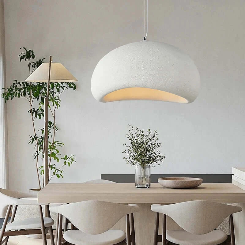 White Nordic minimalist pendant light illuminating a dining table with a vase of flowers in a stylish modern interior.